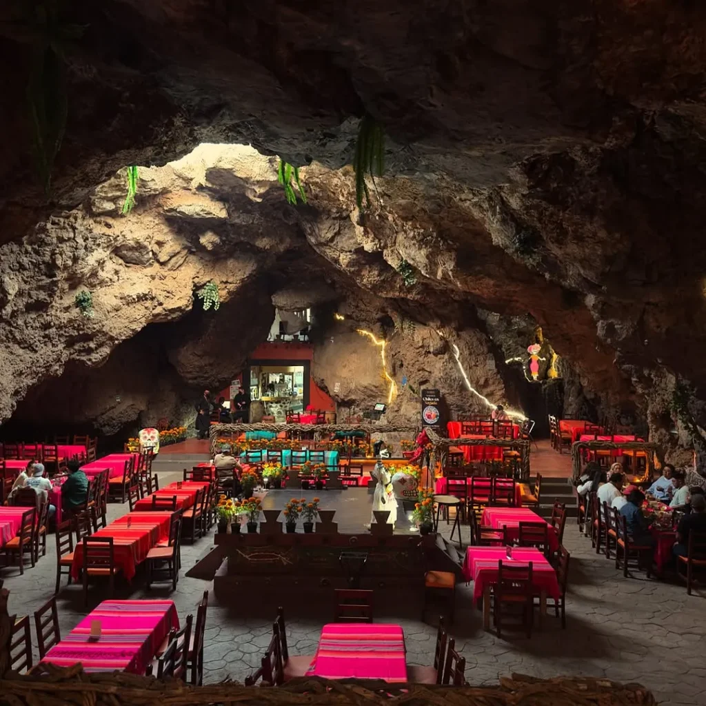 Mesas con manteles rosas y flores de cempasúchil llenan la cueva volcánica del restaurante La Cueva en Teotihuacán