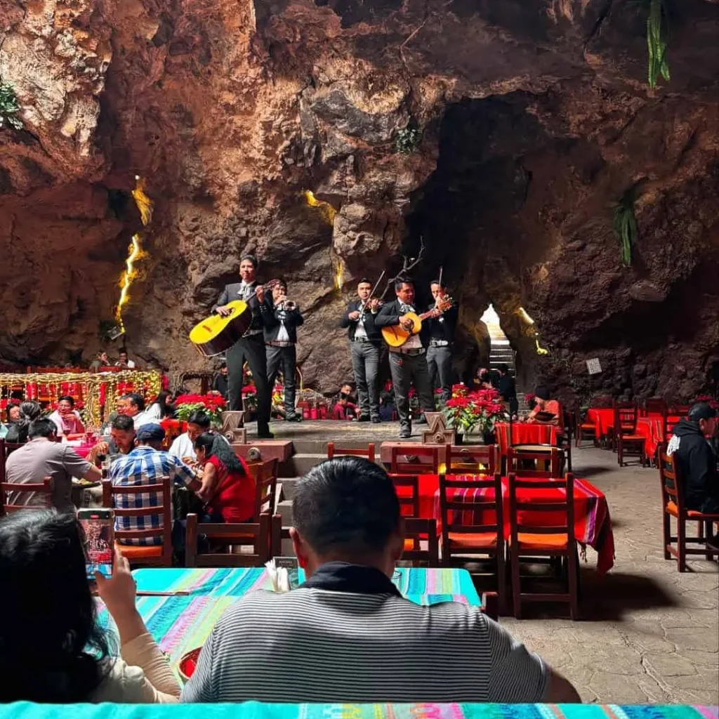 Un mariachi toca en el escenario de piedra mientras los comensales desayunan en el restaurante La Cueva en Teotihuacán