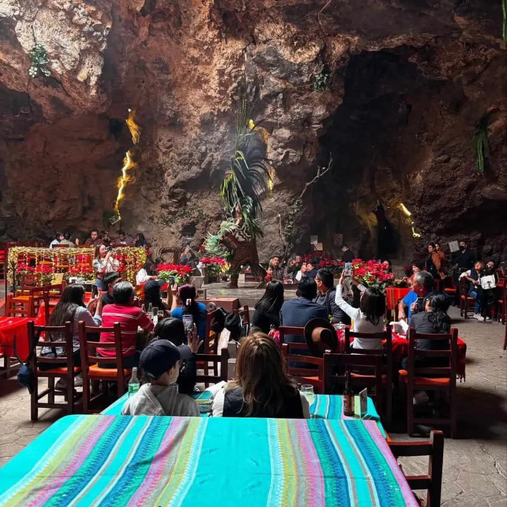 Manteles de sarape turquesa visten las mesas frente al escenario del restaurante La Cueva en Teotihuacán